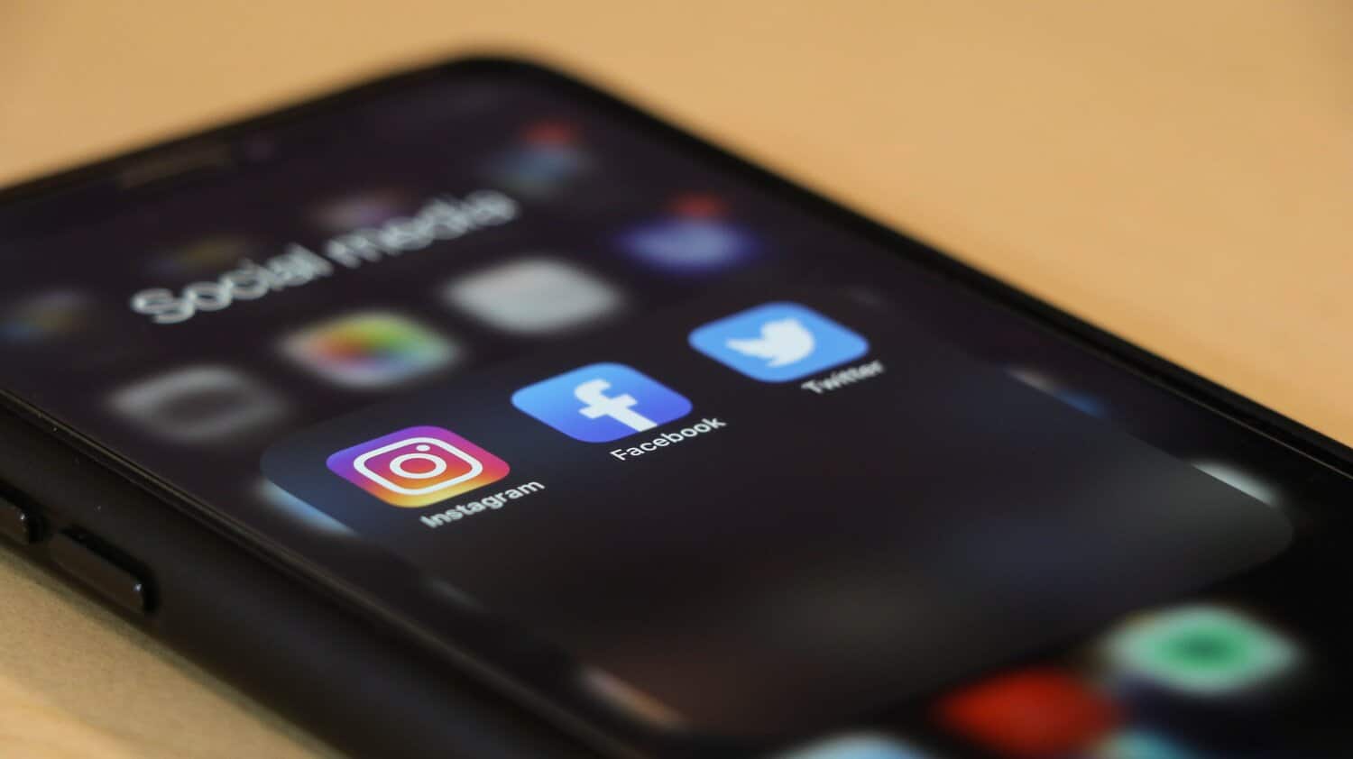 iPhone displaying a social media folder with Instagram, Facebook, and Twitter